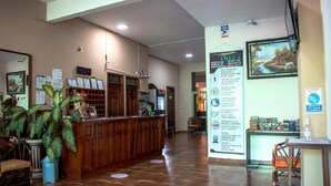A reception area with a wooden counter, potted plants, and informational posters on the wall.