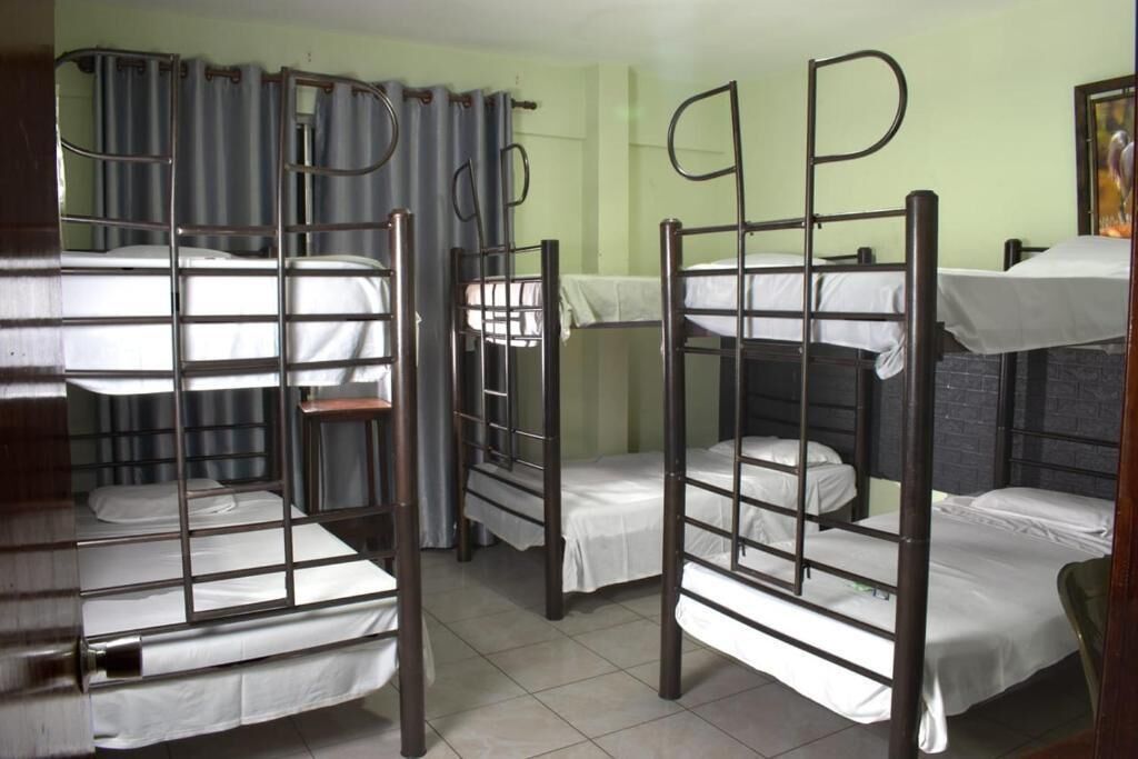 A dormitory room with bunk beds, curtains, and a tiled floor.