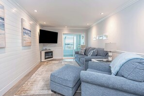 Ein modernes Wohnzimmer mit einer grauen Sofagarnitur, einem flachbildfernseher an der Wand und einem Kamin.
