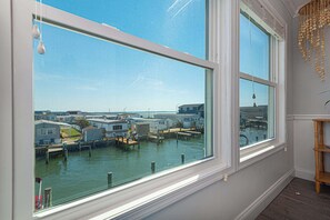 Ein Zimmer mit großen Fenstern und Blick auf einen Yachthafen mit vertäuten Booten und Häusern.