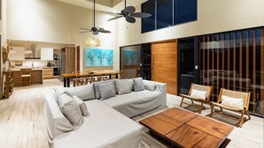 Un salon moderne avec un canapé d’angle, une table basse en bois et deux fauteuils en osier.