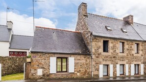 A stone building with a sloped roof, multiple windows, and a visible chimney. - Les Escapades - à 10min en voiture de la plage (Saint-Quay-Perros)
