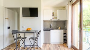 Une cuisine compacte avec un coin repas, un téléviseur à écran plat et une vue à travers une porte vitrée.