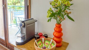 Une machine à café, un bol contenant des sachets de thé Lipton et un vase avec des fleurs, le tout posé sur une table en bois.