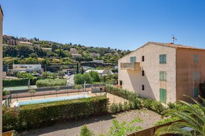A residential area with a building featuring a balcony, a swimming pool, and a hilly backdrop. - L’Escapade du Ponant - À 3 km de la plage (Saint Raphael)