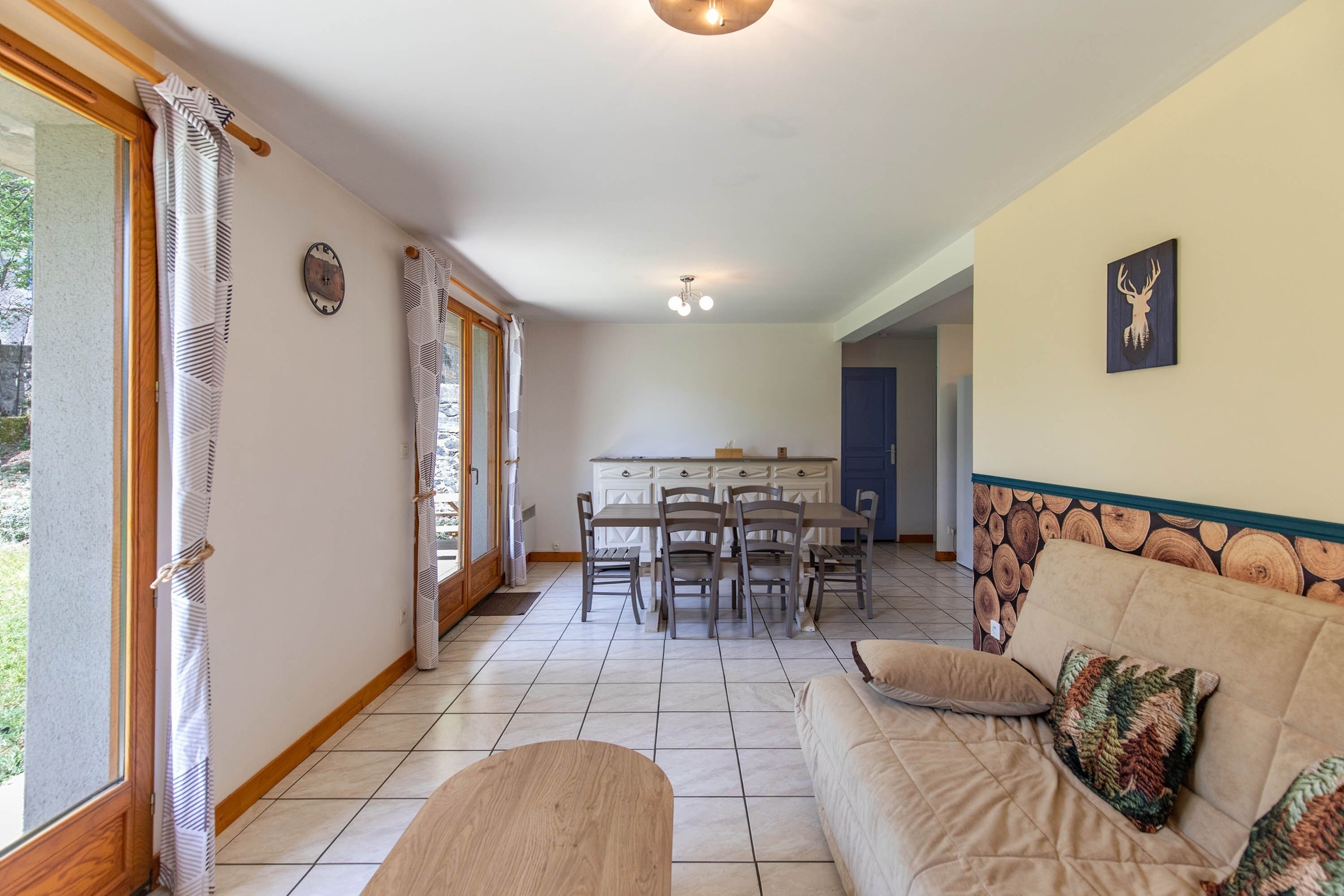 Un salon avec un canapé, une table à manger et des chaises, un coin cuisine et une porte donnant sur un espace extérieur.