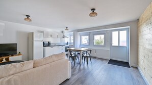 A modern apartment with a living room, kitchen, dining area, and large windows. - L’Escale morbihannaise – Appt à 15 min de la plage (Muzillac)