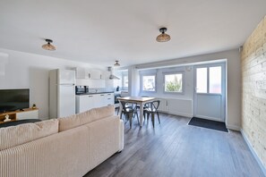 Un appartement moderne comprenant un salon, une cuisine, un coin repas et de grandes fenêtres.