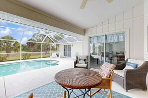 A covered outdoor area with a pool, wicker furniture, and a glass door leading to a patio. - Spacious home with outdoor space & private pool (Rotonda West)