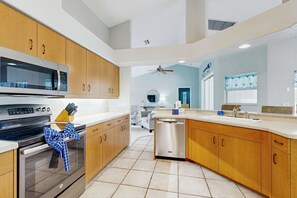 A modern kitchen with wooden cabinets, stainless steel appliances, and a dishwasher. - Spacious home with outdoor space & private pool (Rotonda West)