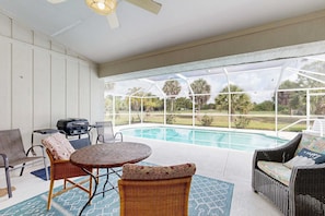 A covered outdoor area with a pool, wicker furniture, and a grill. - Spacious home with outdoor space & private pool (Rotonda West)
