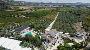 Vista aerea di un vigneto con file di viti, una piscina e un edificio con tetto in tegole.