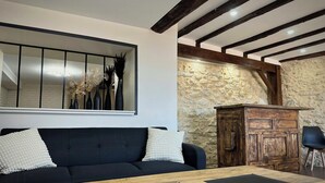 A modern living room with a black sofa, wooden coffee table, and a stone wall. - Villa with Pyrenees view near Foix (Cassagne)