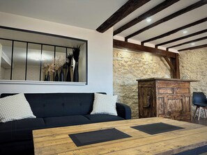 A modern living room with a black sofa, wooden coffee table, and a stone wall. - Villa with Pyrenees view near Foix (Cassagne)