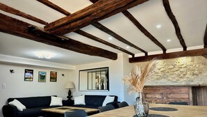 A dining area with a wooden table, chairs, a sofa, and a stone fireplace. - Villa with Pyrenees view near Foix (Cassagne)