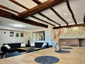 A dining area with a wooden table, chairs, a sofa, and a stone fireplace. - Villa with Pyrenees view near Foix (Cassagne)