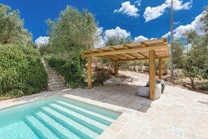 A pool with clear water, a wooden pergola, stone steps, and outdoor furniture. - Trullo with private pool among olives in Ostuni (Ostuni)