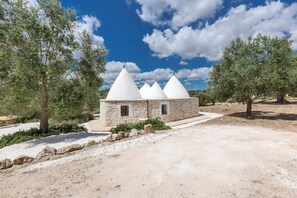 A stone building with three conical structures, surrounded by olive trees and a clear sky. - Trullo with private pool among olives in Ostuni (Ostuni)