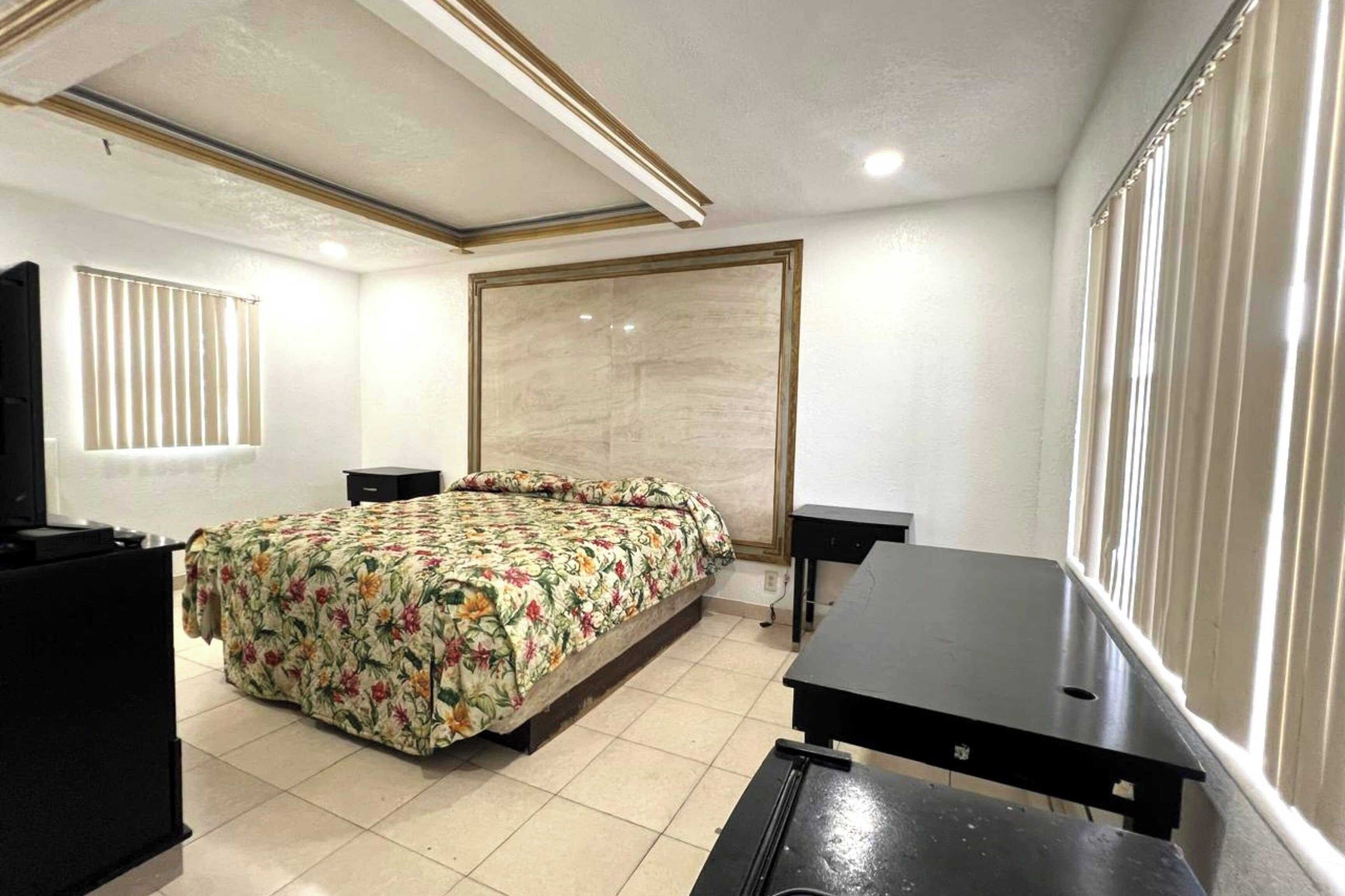 A bedroom with a bed, a desk, and a TV.