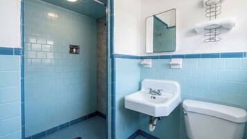 Un baño con azulejos azules, un lavamanos blanco y un inodoro.