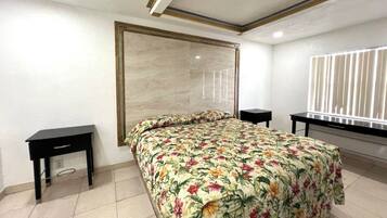 Un dormitorio con una cama grande, dos mesitas de noche, un ventanal con persianas y una pared de acento de mármol.