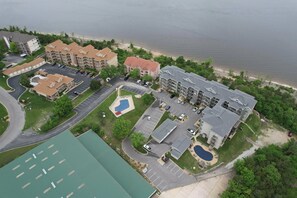 An aerial view of a residential complex with multiple buildings, parking areas, and a beach in the background. - Shoreline Haven Luxury Table Rock Lake (Hollister)