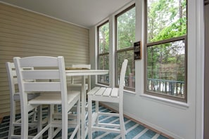 A room with a white table and chairs, large windows with a view of trees, and a blue patterned rug. - Shoreline Haven Luxury Table Rock Lake (Hollister)