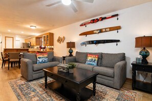 A living room with a sofa, coffee table, and a kitchen in the background. - Shoreline Haven Luxury Table Rock Lake (Hollister)