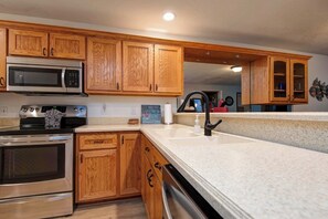 A modern kitchen with wooden cabinets, stainless steel appliances, and a granite countertop. - Shoreline Haven Luxury Table Rock Lake (Hollister)