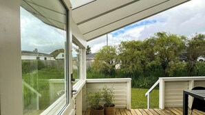 Eine Holzterrasse mit einer Glastür, die zu einem Garten führt.