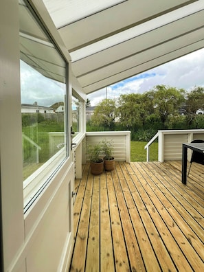 A wooden deck with a glass door leading to a garden area. - Modern house at Sønderballe with private beach (Haderslev)