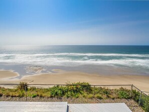 A beach view with a wooden deck and a chain-link fence. - Oceanfront Dreams~3 bedroom, 2200 square feet (Lincoln City)