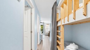 Ein Flur mit einem Etagenbett, einer Tür und Blick in einen Raum mit einem Bett und einer Lampe.