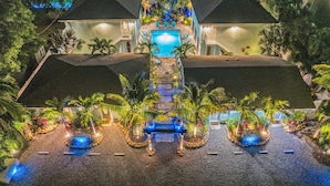 Un resort con piscina, palmeras y una entrada bien iluminada.