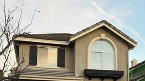 A two-story house with a garage, a large arched window, and a small balcony.
