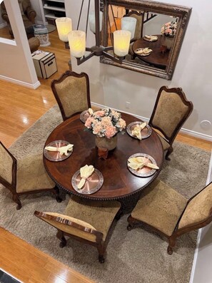A dining area with a round table, chairs, a vase of flowers, and a mirror on the wall.