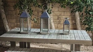 A wooden picnic table with three lanterns.