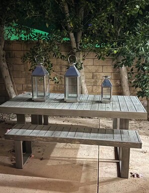 A wooden picnic table with three lanterns.