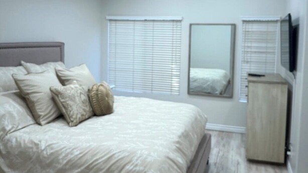 A bedroom with a bed, bedside tables, a mirror, and a wardrobe.