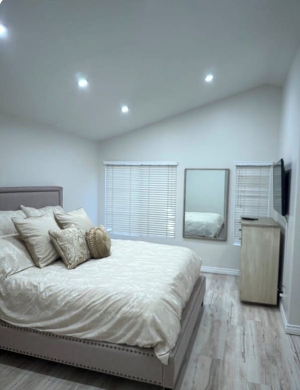 A bedroom with a bed, bedside tables, a mirror, and a wardrobe.