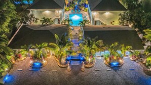 Ein Resort mit Pool, Palmen und einem gut beleuchteten Eingangsbereich.
