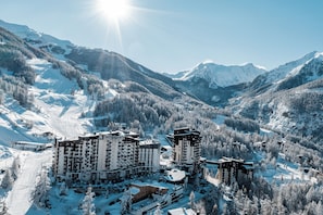 Ein schneebedecktes Bergresort mit mehreren Hochhäusern, Skipisten und bewaldeten Gebieten.