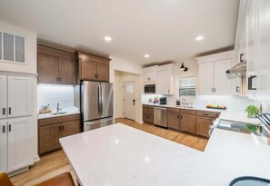 A modern kitchen with white cabinets, stainless steel appliances, and a marble countertop. - Lakefront Luxury Condo w/ Fire Pit, 10 Min. to Dow (Hot Springs)