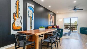A dining area with a wooden table and chairs, a sofa, and artwork on the walls.