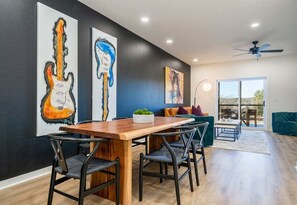 A dining area with a wooden table and chairs, a sofa, and artwork on the walls. - Lakefront Luxury Condo w/ Fire Pit, 10 Min. to Dow (Hot Springs)