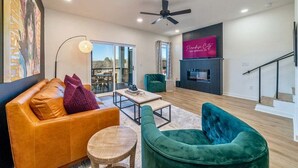 Un salon moderne comprenant un canapé, des fauteuils, une table basse et un téléviseur.