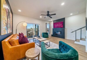 A modern living room with a sofa, chairs, a coffee table, and a TV. - Lakefront Condo w/ Fire Pit, Pool, Near Oaklawn (Hot Springs)
