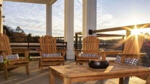 Un espace extérieur abrité, aménagé avec du mobilier en bois et offrant une vue sur le paysage.