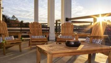 A covered outdoor seating area with wooden furniture and a view of the landscape.