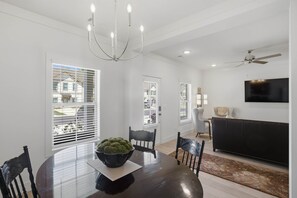 A dining area with a round table, chairs, a chandelier, and a TV on the wall. - Wire Tiger-Close to Campus (Auburn)